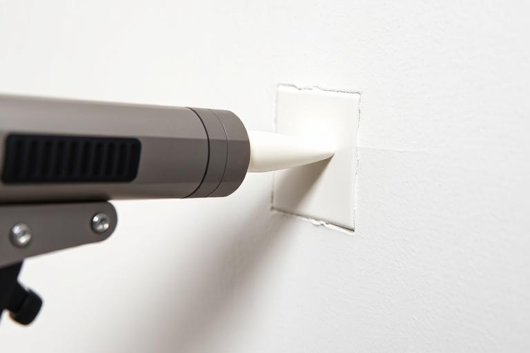 Caulking gun applying sealant into a wall joint